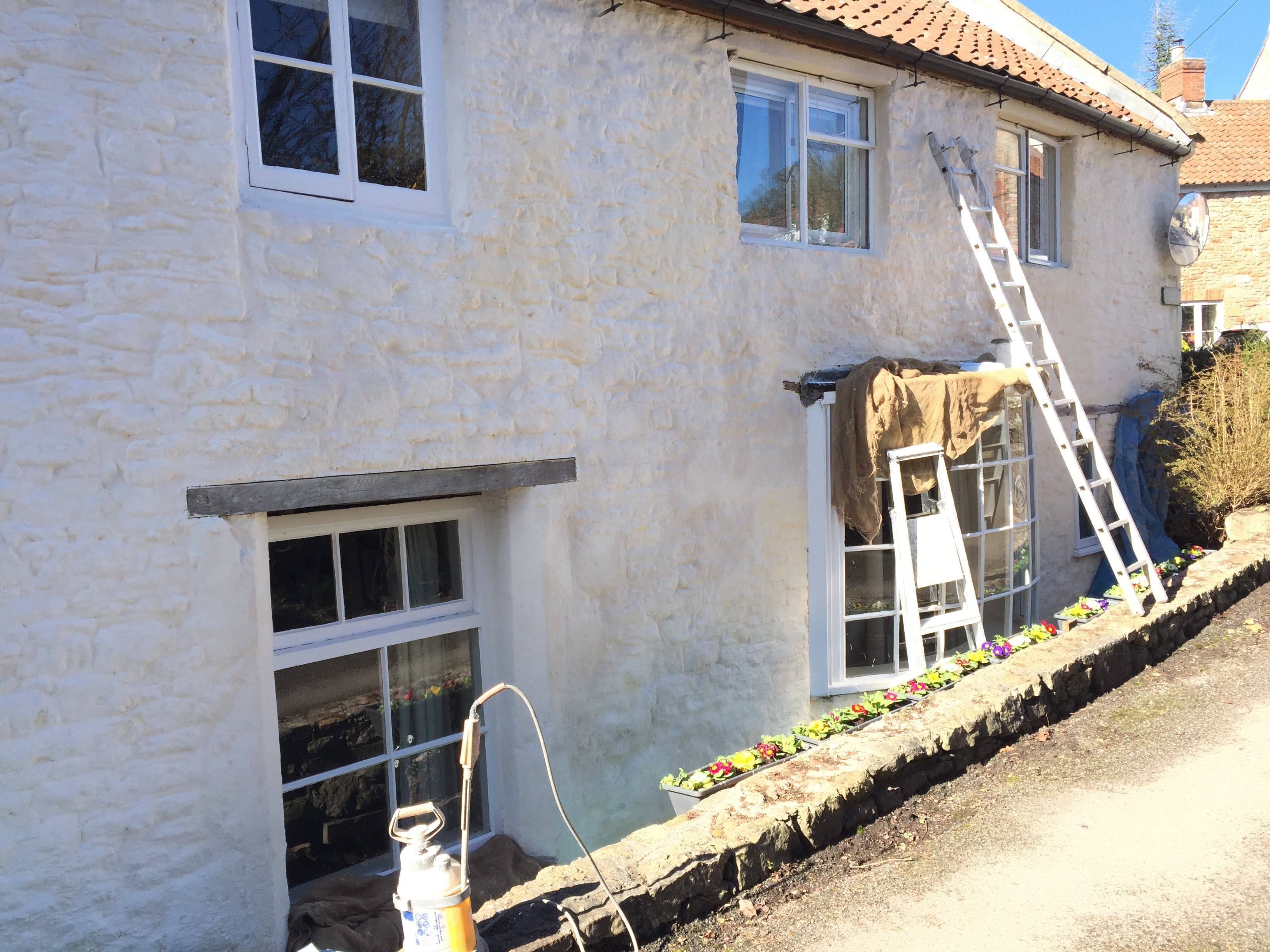 Lime wash restoration in progress on a stone cottage exterior